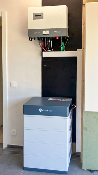 Moderne thuisbatterijopstelling met Pylontech toren en Solis omvormer, strak geplaatst tegen zwarte wand