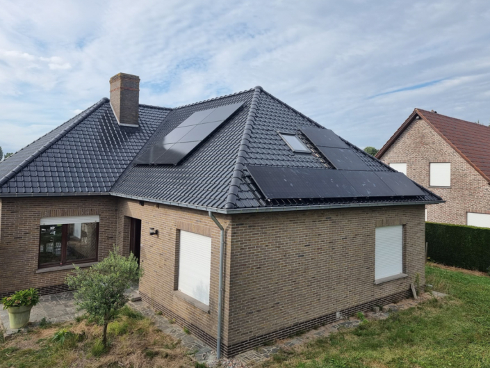 Zwarte zonnepanelen op beide dakvlakken van een woning met zwart pannendak, schoorsteen en dakvenster centraal
