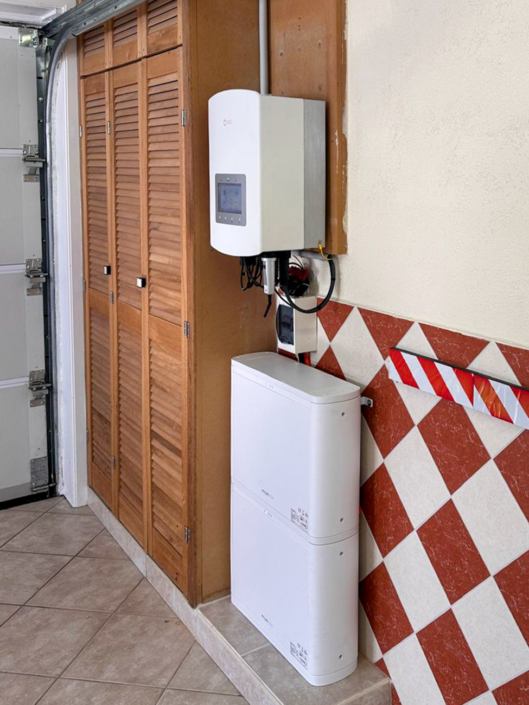 Thuisbatterijopstelling met witte batterijtoren onder Solis omvormer in garage met tegelwand