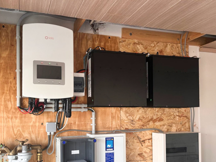 Zwarte batterijmodules horizontaal gemonteerd op houten wand met Solis omvormer erboven