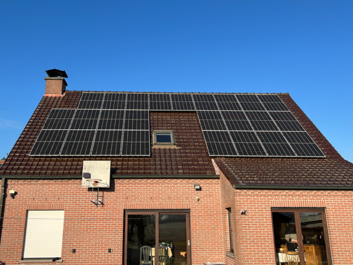 Zonnepanelen op schuin dak van een woning met roodbruine dakpannen in het Meetjesland