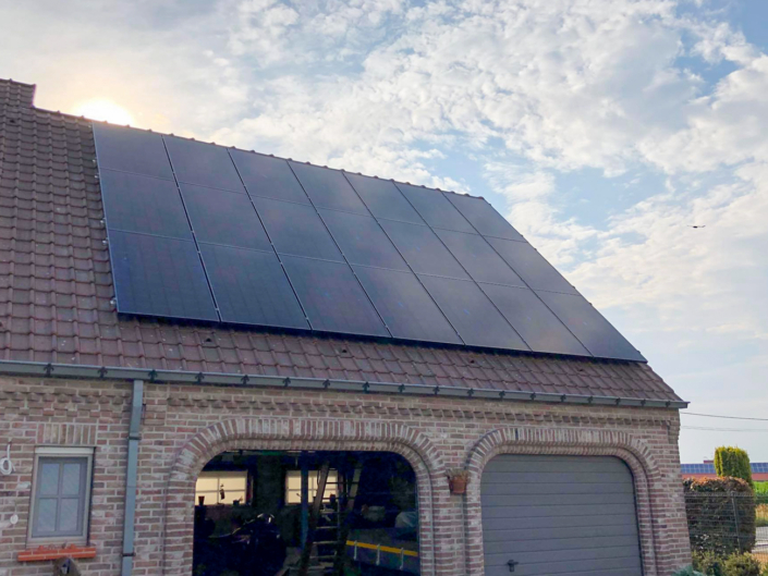 Zwarte zonnepanelen op hellend dak boven garage met landelijk uitzicht