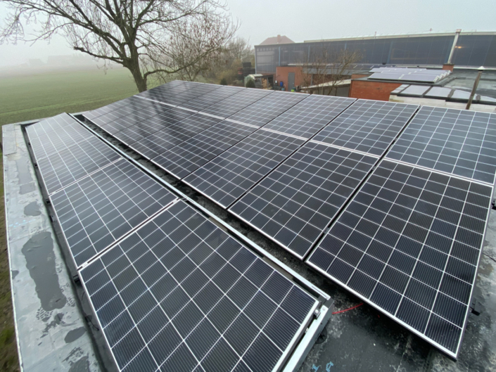 Zonnepanelen op plat dak in landelijke omgeving met mistig veld op achtergrond