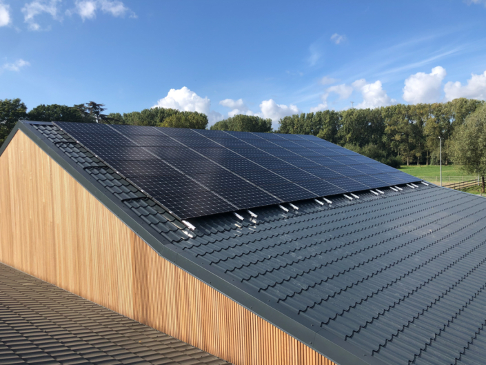 Zonnepanelen op stalen dak van houten bijgebouw tussen het groen