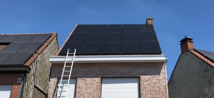 Zwarte zonnepanelen op rijwoning met ladder en dakrand in beeld
