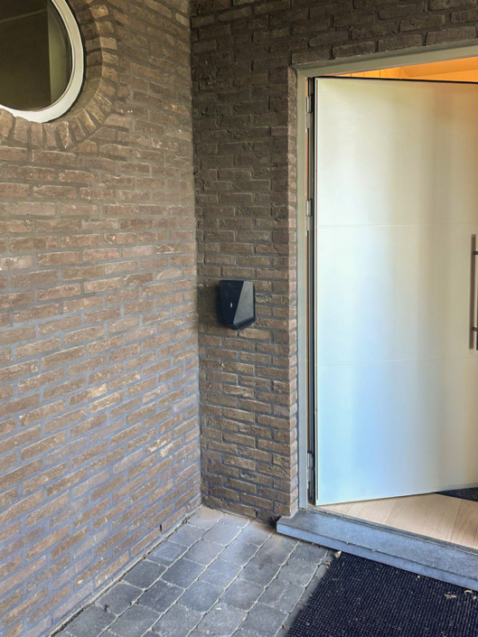 Elegante zwarte laadpaal naast de voordeur van een woning in regio Eeklo, onopvallend en functioneel geplaatst